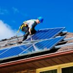 operaio sul tetto che fa manutenzione sui pannelli solari